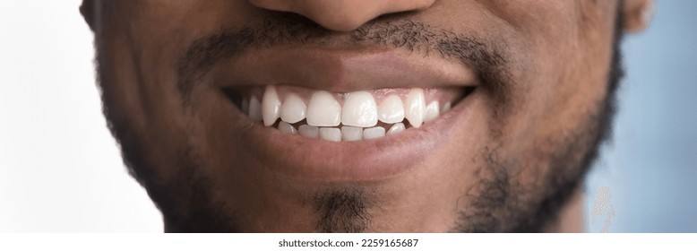 Happy African man posing with toothy smile, showing healthy white teeth. Clinic patient satisfied with dentist service, enamel cleaning, whitening, dental care, correction. Banner shot, close up