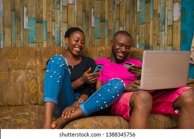 happy African man shopping with his card on his laptop and a lady pressing her phone with a smiling face