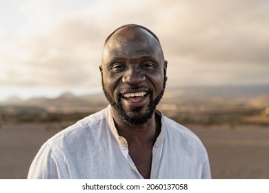Happy African man smiling in camera on the beach during summer vacation