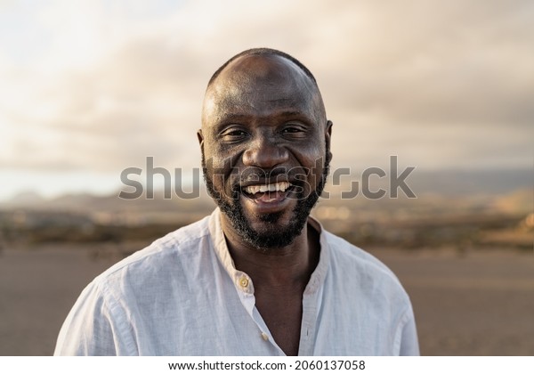 Happy African man smiling in camera on the beach\
during summer vacation