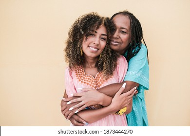 Happy african mother with adult daughter hug each other while wearing traditional dress - Family love