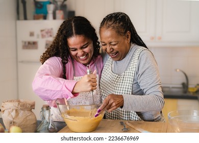 Happy African mother and daughter having fun preparing a homemade dessert - Powered by Shutterstock