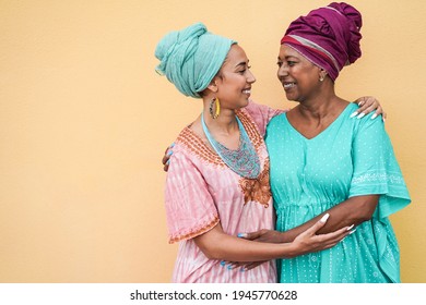 Happy african mother and daughter hugging each other while wearing traditional dresses - Focus on mother face
