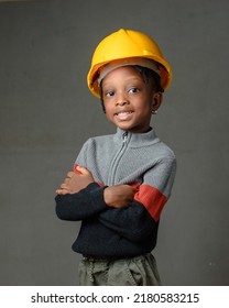 A Happy African Nigerian Girl Child With Yellow Safety Helmet Modeling As A Professional Construction Or Civil Engineer, Architect And Builder Among Others