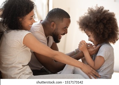 Happy African Parents And Little Cutie Daughter Spending Weekend At Home, Loving Father Tickling Kid Girl Play Enjoy Priceless Time Together, Concept Of Happy Wealthy Family Have Fun Activity Concept