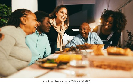 Happy african people eating dinner together at home terrace outdoor - Holidays and family concept - Soft focus on senior woman face - Powered by Shutterstock