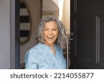 Happy african senior caucasian women opening door and welcoming somebody. Spending time together at home.