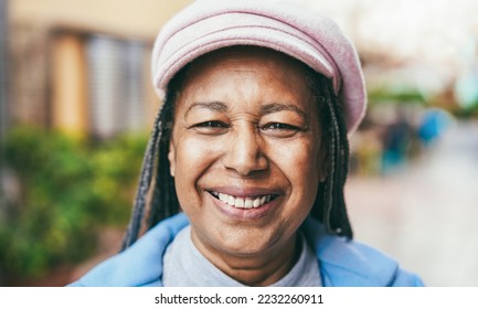 Happy african senior woman smiling on camera outdoor during winter day - Focus on face - Powered by Shutterstock