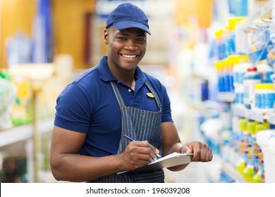 Happy African Shop Assistant Checking Stock In Supermarket