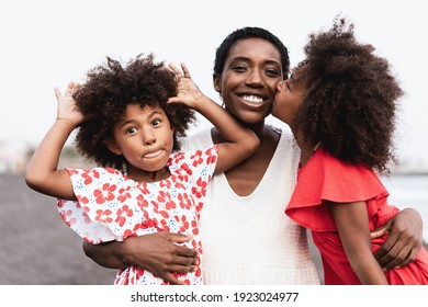 Happy african sister twins kissing mother on the beach - Focus on mother face