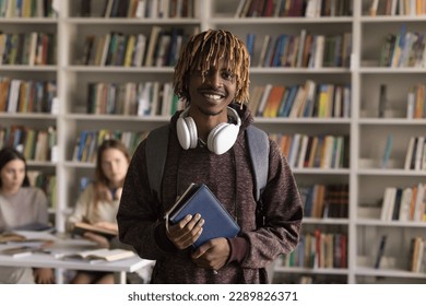 Happy African student guy pose in university library, smile look at camera, enjoy studies, feels interested and motivated to gain new skill and knowledge, get highly demanded profession for future job - Powered by Shutterstock