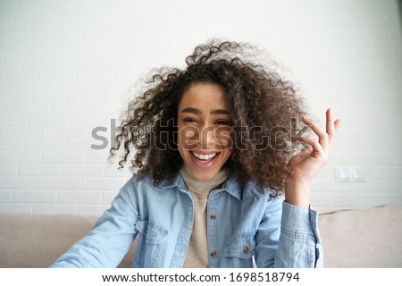 Happy african teen girl blogger talking to camera video calling, recording vlog. Happy afro young woman laughing distance chatting at home office. Funny social media influencer streaming. Webcam view Stock photo © 
