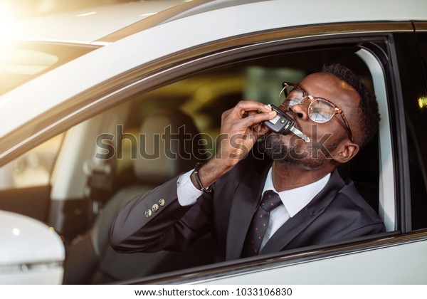 happy african vehicle buyer inside his new car kiss
him car key
