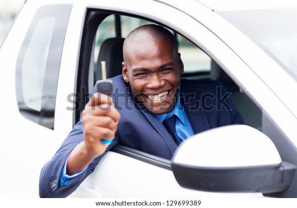 happy african vehicle buyer inside his new car with\
car key