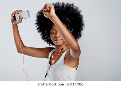 Happy African Woman With Afro And Casual Clothing Dancing To The Music She Is Listening To On Her Phone