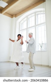 Happy African Woman Dancing Together With Senior Man During Dance Lesson In Studio