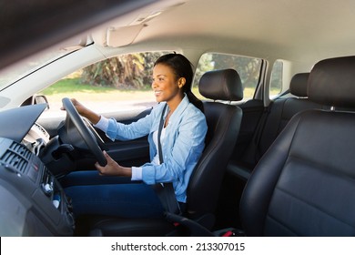 happy african woman driving a new car