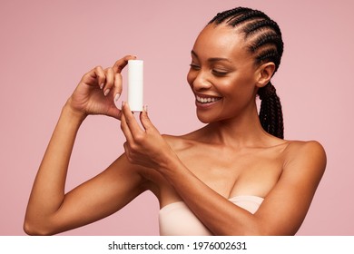 Happy African Woman Holding A Cosmetic Product. Female Model With Beautiful Skin Showing A Skincare Product.