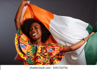 Happy african woman in national clothes smiling and posing with a flag Ivory Coast, C te d'Ivoire isolated over a gray background - Shutterstock ID 1591723756