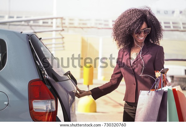 happy\
african woman with shopping bags opening\
car