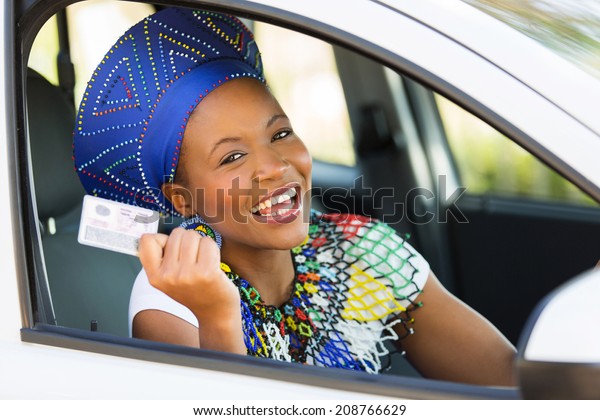 happy african woman showing her driver\'s license she\
just got