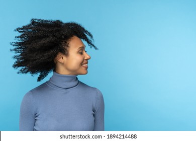 Happy African woman smiling, has good mood, dancing with her black curly hair flying, isolated on studio blue background. Excited Afro American girl with flying hairstyle. Positive life concept.  - Powered by Shutterstock