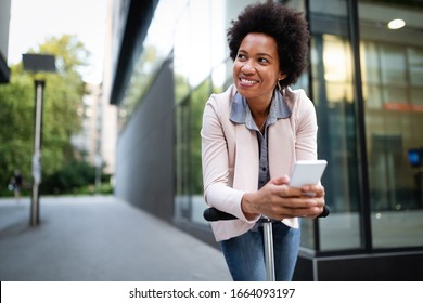 Happy african woman standing near kick scooter and using mobile phone in city - Powered by Shutterstock