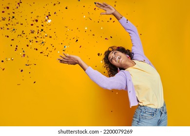 Happy African Woman Throwing Confetti And Smiling While Standing Against Yellow Background