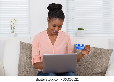 Happy African Woman Using Debit Card For Shopping Online On Laptop