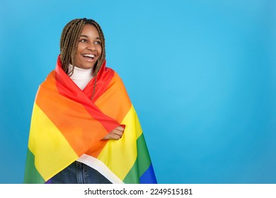 Happy african woman wrapped in a lgbt rainbow flag