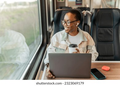 Happy African young businesswoman enjoying in train ride while drinking takeaway coffee. Business trips, tourist solo travel. - Powered by Shutterstock