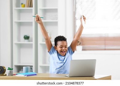 Happy African-American boy after passing school test online at home