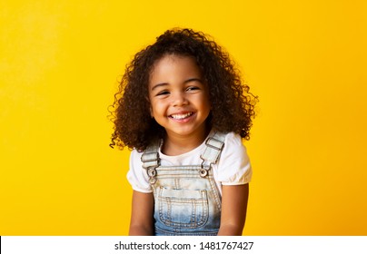 Happy african  american child girl smiling to camera over yellow background