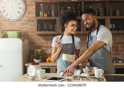 Happy African-american Couple Baking Pie And Using Digital Tablet In Loft Interior.