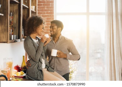 Happy african-american couple laughing during morning coffee break at kitchen interior, copy space - Powered by Shutterstock