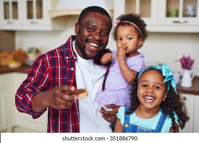 Happy African-American man with adorable daughters looking at camera