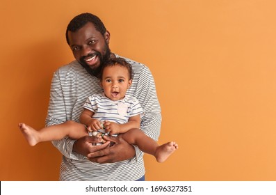 Happy African-American Man With Cute Baby On Color Background