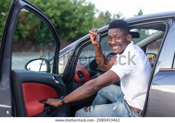 A happy African-American man holds the car keys.\
Car sales and rentals.