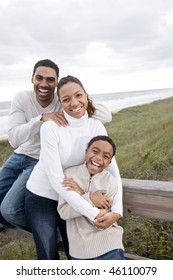 Happy African-American Parents With Ten Year Old Boy Smiling And Hugging At Beach