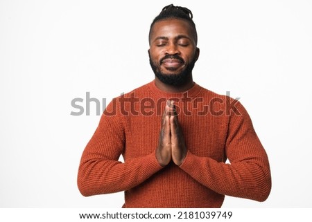 Happy african-american young man meditating praying to God, feeling zen-like, relaxing resting concentrating isolated in white background
