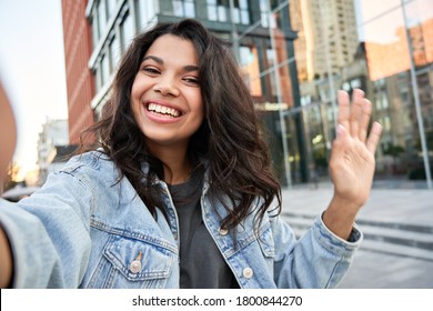 Happy Afro American hipster teen girl blogger influencer recording vlog holding looking at camera. Black woman travel vlogger shooting blog, streaming, video calling on urban city street, headshot.