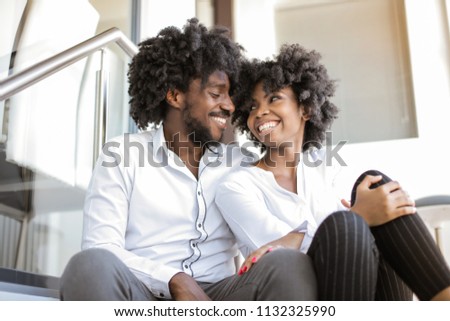 Happy Afro couple sitting on a stairs and smiling.