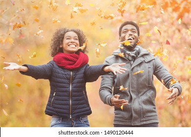 Happy Afro Couple Throwing Autumn Fall Leaves, Walking And Having Fun In Park