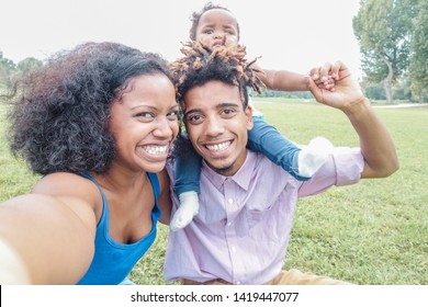 Happy afro family making selfie with smartphone camera - African young parents and their daughter having fun with new trends technology - Love concept - Main focus on mother face - Powered by Shutterstock