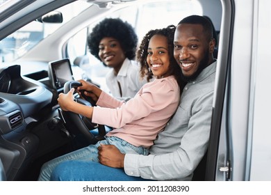 Happy Afro Family Sitting In New Car, Going On Test Drive, Buying Automobile In Dealership Store. Black Customers Checking Vehicle Before Purchase Or Rental, Posing Inside Car Salon, Smiling At Camera