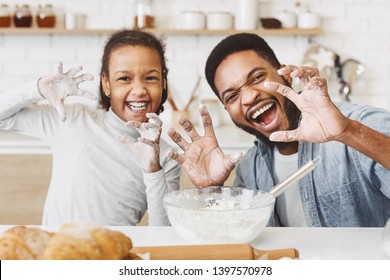 Happy afro father and daughter with funny growling faces, having fun, cooking together at kitchen - Powered by Shutterstock