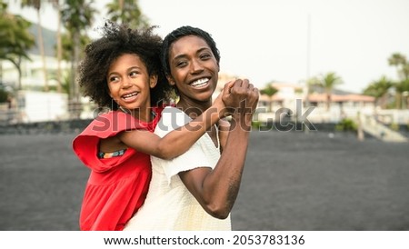 Happy Afro mother and daughter having fun on the beach during vacations - Lovely family lifestyle concept