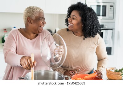 Happy Afro mother and daughter preparing lunch together in modern house kitchen - Food and parents unity concept  - Powered by Shutterstock