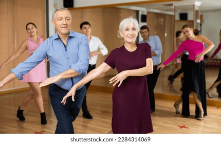 Happy aged couple attending group choreography class, learning upbeat dynamic partner swing dance. Concept of active hobbies for older people - Powered by Shutterstock