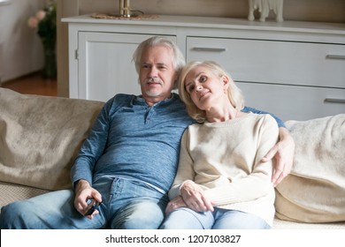 Happy Aged Couple Lying On Cozy Couch At Home Watching Movie On TV, Senior Husband And Wife Cuddle Relaxing On Sofa Spending Romantic Time On Weekend, Elderly Spouses Hugging Enjoying Rest Together